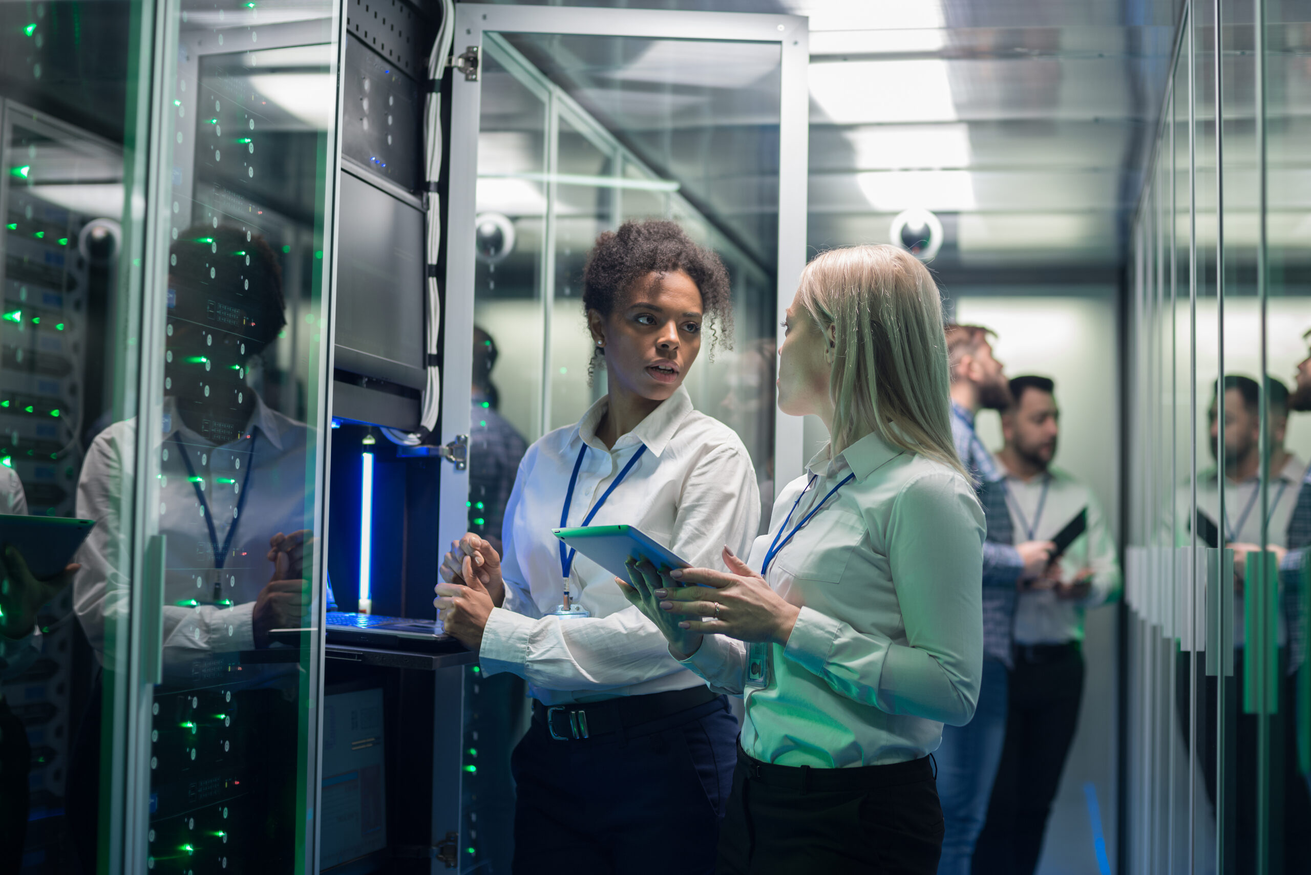 Two women are working in a data center with rows of server racks